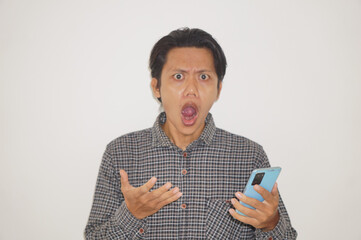 Young Asian man wearing black shirt surprised while looking at smartphone isolated on white background. - obrazy, fototapety, plakaty