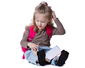 Girl child with backpack sitting looking smiling reading book on white background isolation. Childhood, education, products children
