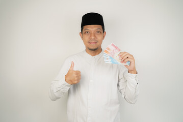 happy asian muslim man holding money, wearing arabic costume on isolated background - obrazy, fototapety, plakaty