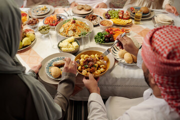 Unrecognizable Muslim Family Sharing Food During Dinner