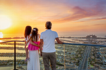 A family on holidays enjoys the beautiful view of The Palm island in Dubai, UAE, during a golden sunset