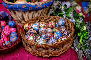 Beautiful handmade colorful Easter eggs in a basket and Easter palms on stall during fier. Kurpie, Poland	
