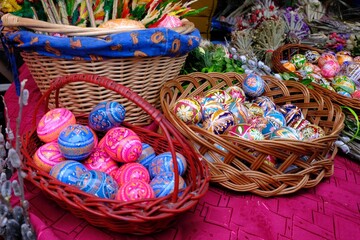 Fototapeta na wymiar Beautiful handmade colorful Easter eggs in a basket and Easter palms on stall during fier. Kurpie, Poland 