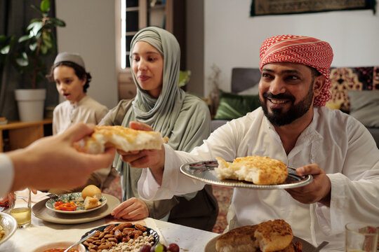 Middle Eastern Man Sharing Bread With Relatives At Festive Dinner