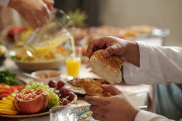 Hands Of Man Tearing Off Piece Of Bread During Dinner