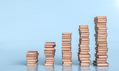 Increasing stacks of books on blue background - 769571589