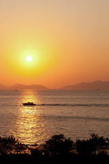 Fototapeta premium Golden Sunset Serenity. A tranquil sunset over the ocean, with a boat silhouetted against the warm hues of the sky. Calm and inspiring.
