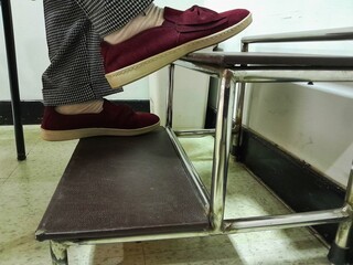 Elderly woman in red sneakers at two step stainless steel medical footstool. - obrazy, fototapety, plakaty