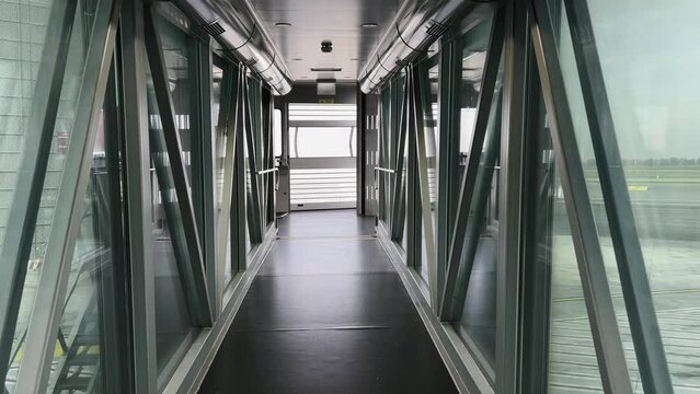 First-person POV walking inside empty and inoperative passenger boarding bridge without airplane