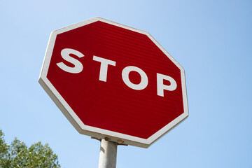 Low angle view of a red Spanish STOP road sign, against a clear blue sky.