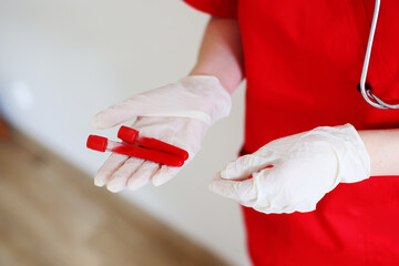 Hand with latex glove holding blood sample vial in front of blood test form
