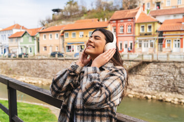 One young girl or woman is listening to music on her wireless headphones and enjoying the sun outdoors	
