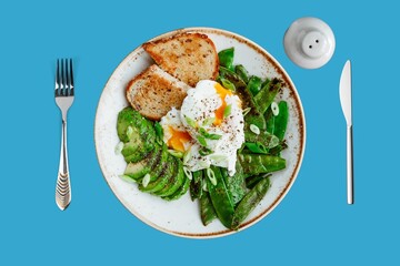 Delicious vegetarian breakfast - zucchini fritters, poached egg, avocado and bread on a light background, top view - obrazy, fototapety, plakaty