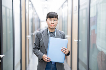 White-collar worker holding folder in office corridor