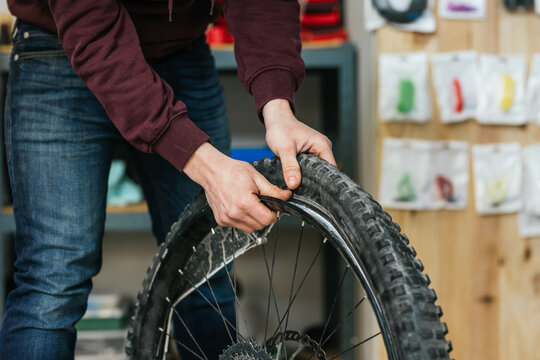 Close-up of hands and a bicycle wheel while the tire is being removed from the rim.