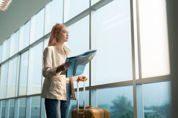 Happy young woman asian is stand in airport near suitcase and reading map