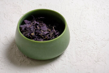 Dry lavender tea in a green bowl on a white background