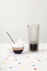 cup of coffee with whipped cream and sprinkles next to a vintage fake crystal decanter