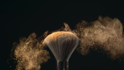 Super slow motion macro shot of makeup brush and golden shiny face powder shake at 1000 fps. Elegant luxury make up cosmetic abstract background. Beauty make-up glitter flying in high speed close up