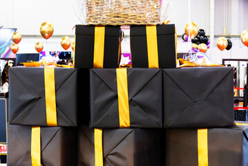 Black and yellow gifts stacked on top of each other. Several black boxes with yellow ribbons make...