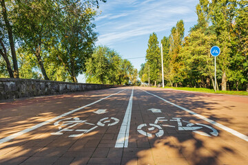 White markings of a bicycle path on an alley in a city park or garden on a sunny summer day