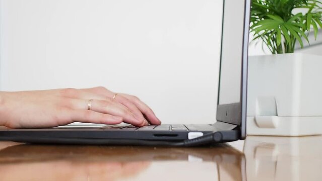 Female hands are typing on laptop notebook keyboard sit at home office desk working online with pc software apps technology concept, close up side view. 