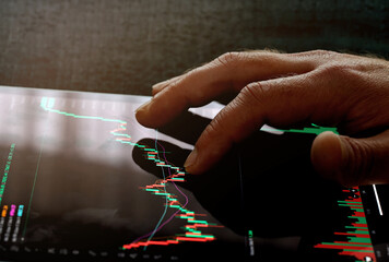 Man's finger pointing on stock price chart graph. An investor check price depth chart on tablet to...
