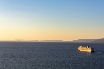 Obraz premium Cruise ship basking in the golden hour light, serene sea, sailing fromthe bay, trending pastel skies. Kusadasi, Aidyn, Turkiye (Turkey)