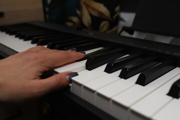 Fototapeta na wymiar A woman's hand plays the piano.