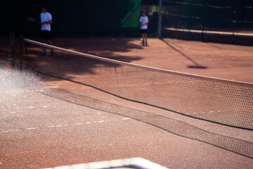friends playing tennis on a clay court, watering and bagging a clay court. doing tennis court...