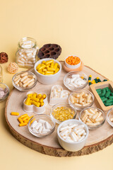 Various vitamins and minerals, food supplements in small jars on a wooden desk. Vitamins and dietary supplements to improve immune system and health. Healthy lifestyle. Vitamin D3, C, A, E.