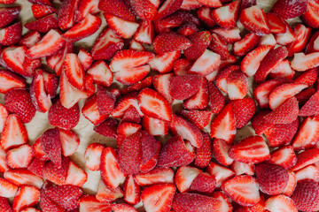 Close-up of a pile of sliced, vibrant red strawberries on a surface, indicative of food preparation...
