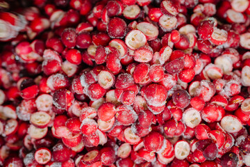A multitude of sliced, frost-covered red berries, clustered together showcasing their fresh, icy textures.