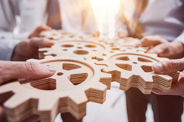 Business people holding wooden gears in office