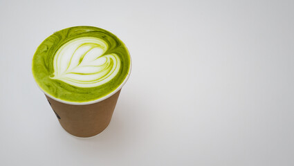green matcha tea 
latte with heart shaped creama pattern in take out paper cup, copy space