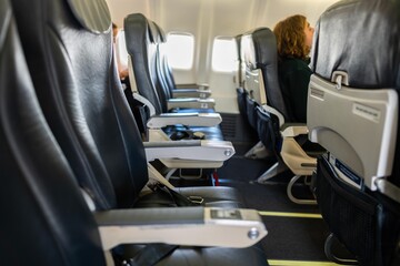 seats inside a plane with seatbealts and chairs in economy seats on an airplane