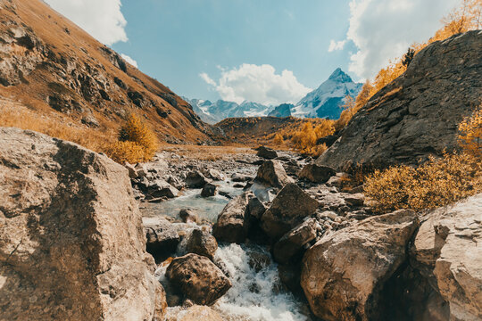 Mountain river made of melted ice. Snowy mountains in the background