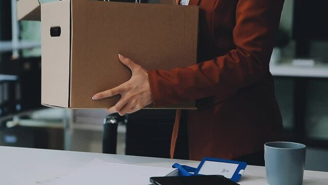 Upset female employee packing belongings in box, frustrated stressed girl getting fired from job ready to leave on last day at work. sad office worker desperate from work