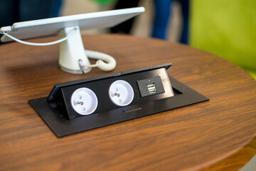 Two hidden sockets and usb charger on a wooden office table close-up