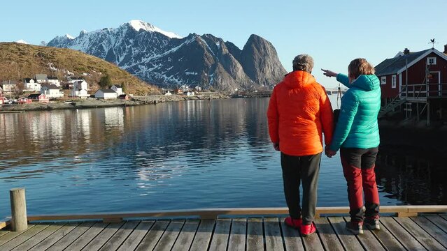 Travelers, walking on a beach surrounded by mountains. A happy loving mature couple enjoys a walk on the seashore in Norway. A man and a woman enjoy a beautiful nature of the Lofoten islands.