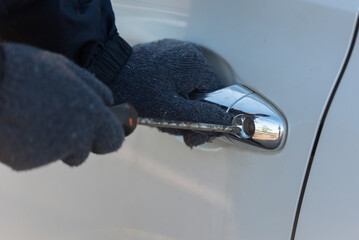 Close-up Man dressed in a black holding screwdriver to break the lock and steal a vehicle on the road, Social destruction, Insurance, Car thief concept. - obrazy, fototapety, plakaty