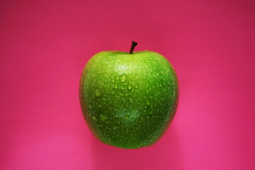 Ripe green apple on pink background