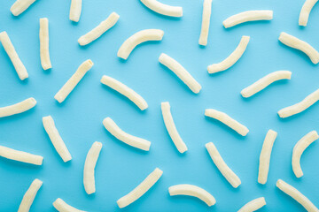 White sticks of potato chips on light blue table background. Pastel color. Closeup. Food pattern. Top down view.