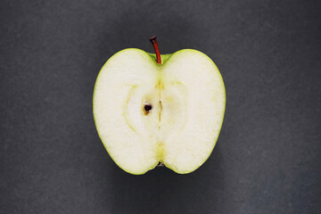 Half a ripe green apple on a gray background