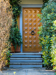 A contemporary design house entrance with a wooden door between lush foliage. Travel to Athens, Greece. - 769679121