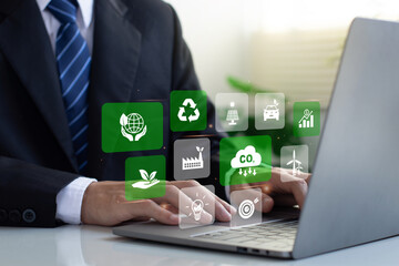 A businessman is working on a laptop with various green icons floating around him, representing...
