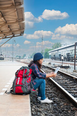 Traveler and tourist asia young women wearing backpack holding map, waiting for a train. Travel Concept.