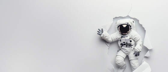 An astronaut in a spacesuit appears to be breaking through a plain white wall, giving a sense of discovery or breakthrough - obrazy, fototapety, plakaty