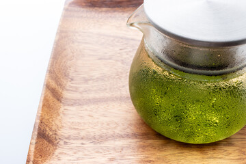 汗をかいたガラスのポットに入った冷たい水出し緑茶