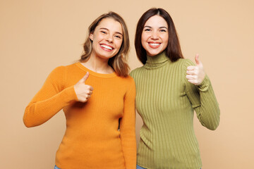 Young smiling happy friends two women they wear orange green shirt casual clothes together show...